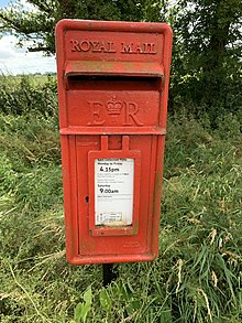 Photo of faded red postbox on a pole